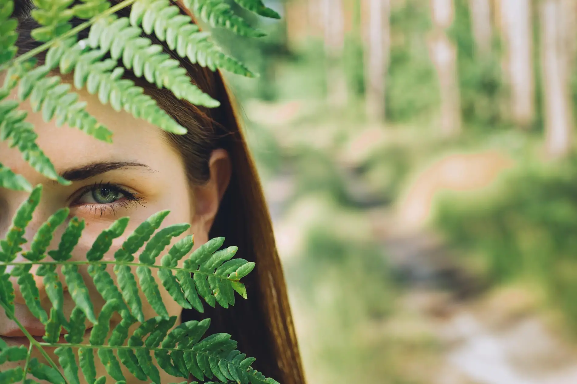 Femme cachant son visage derrière une grande feuille tropicale, symbolisant la protection du gris-gris.